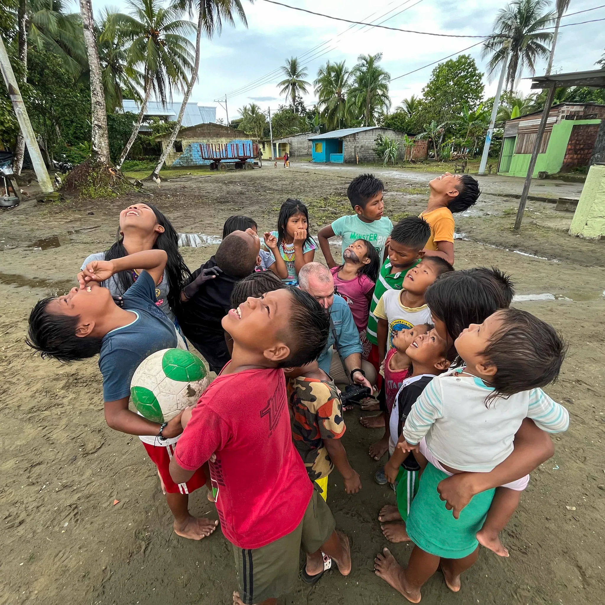 Niñas y niños de una comunidad costera miran juntos hacia el cielo