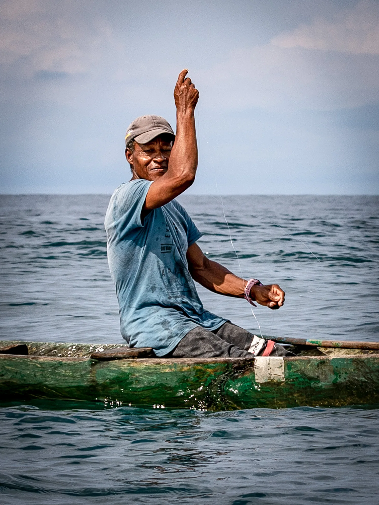 Pescador sostiene una línea desde una canoa sobre el mar